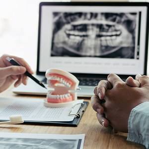 Dentist showing patient model of teeth with X-ray